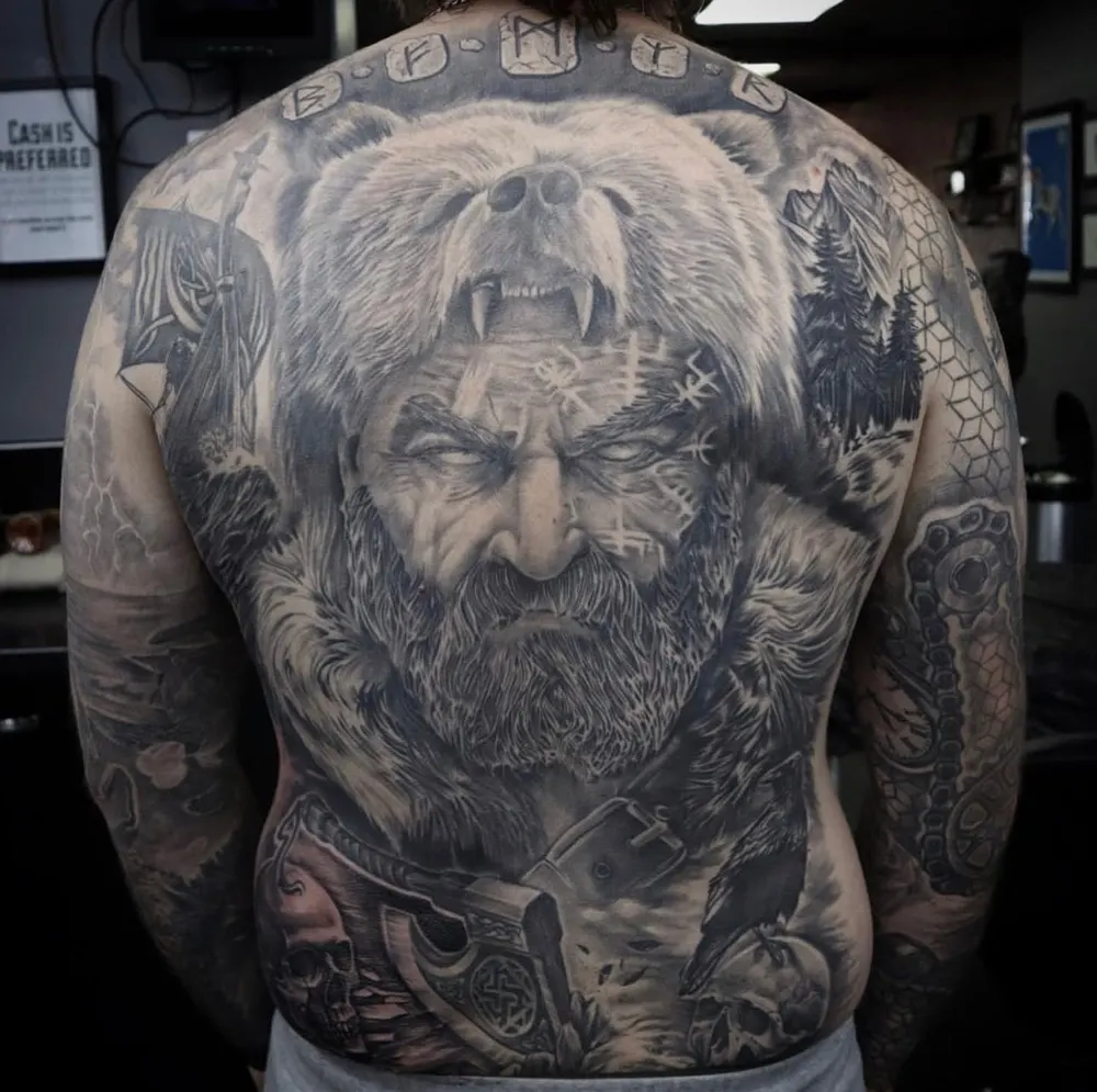 Black and grey full back piece of a bearded god figure