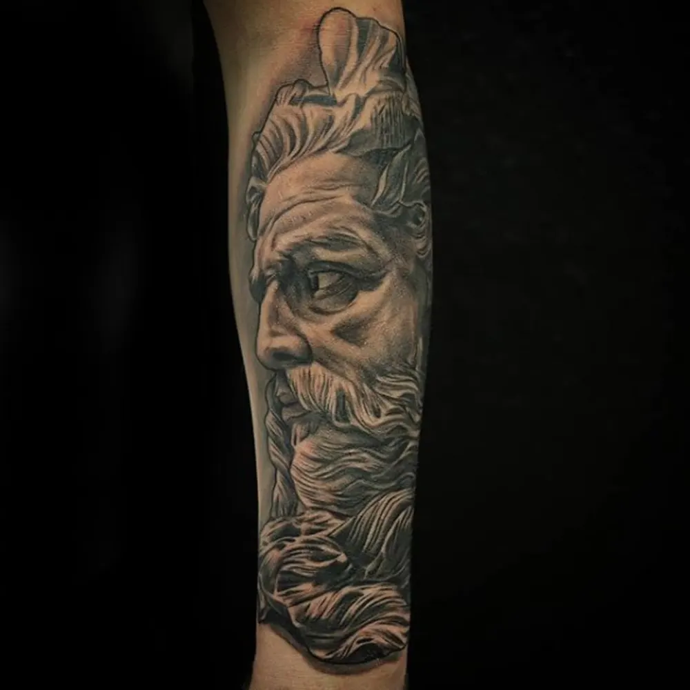 Black and grey Poseidon realism tattoo on a forearm